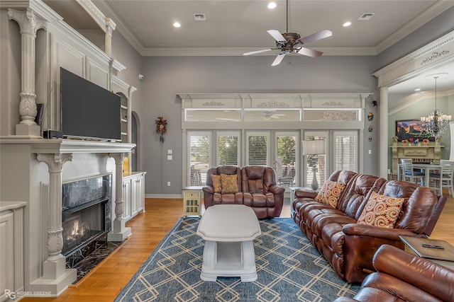 living room featuring crown molding, a fireplace, ceiling fan, and wood-type flooring