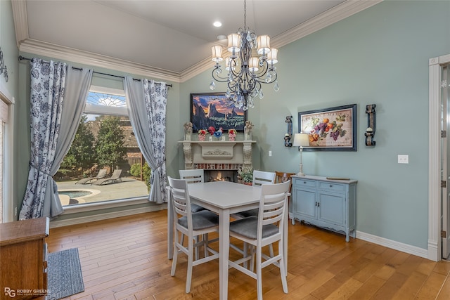 dining room with a fireplace, light hardwood / wood-style flooring, a notable chandelier, and crown molding