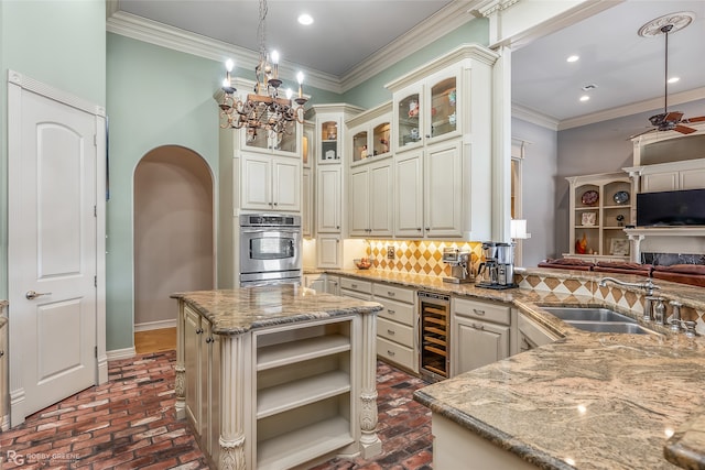 kitchen featuring hanging light fixtures, light stone countertops, beverage cooler, and sink