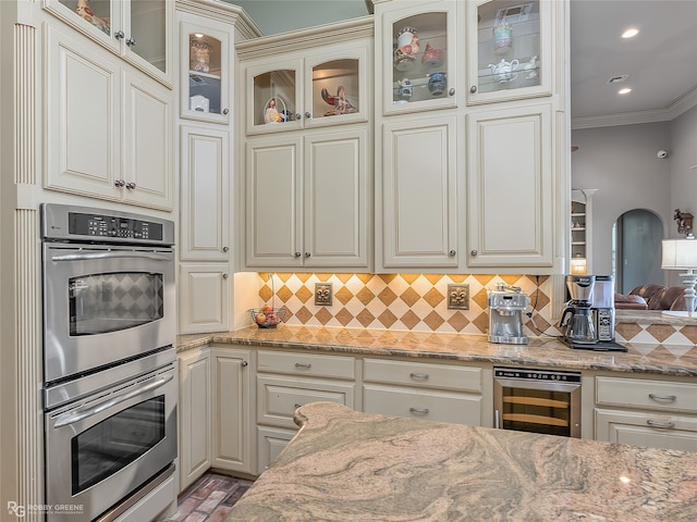 kitchen with stainless steel double oven, ornamental molding, backsplash, and wine cooler