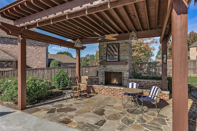 view of patio with an outdoor stone fireplace and ceiling fan