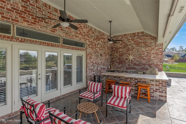 view of patio with ceiling fan, a bar, and an outdoor kitchen