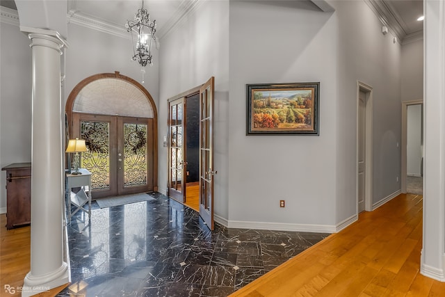 entrance foyer featuring ornate columns, crown molding, french doors, and a towering ceiling