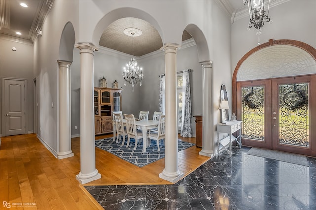 foyer entrance with hardwood / wood-style floors, a notable chandelier, crown molding, and french doors