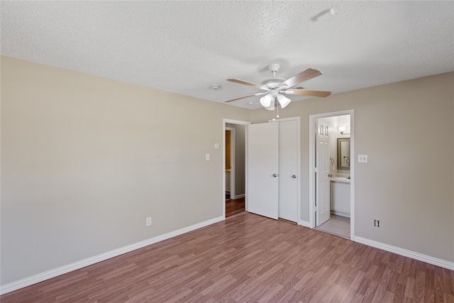 unfurnished bedroom featuring a textured ceiling, ensuite bathroom, ceiling fan, and light hardwood / wood-style floors