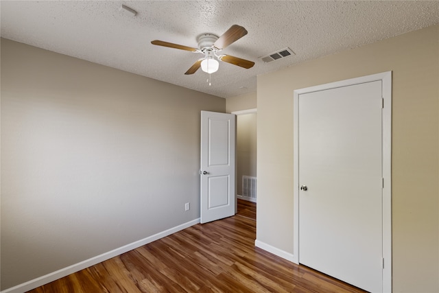 unfurnished bedroom with hardwood / wood-style flooring, ceiling fan, and a textured ceiling