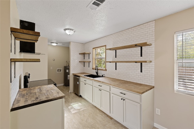 kitchen with wooden counters, white cabinets, plenty of natural light, and sink