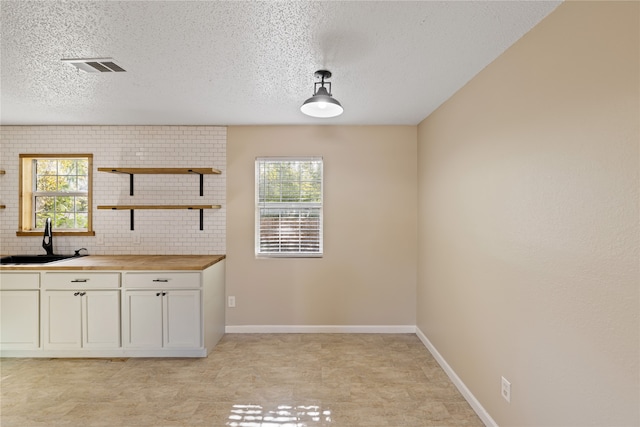 unfurnished dining area featuring a textured ceiling, plenty of natural light, and sink