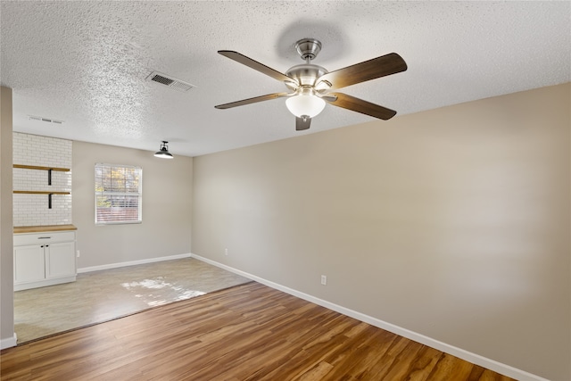 empty room featuring hardwood / wood-style floors, ceiling fan, and a textured ceiling