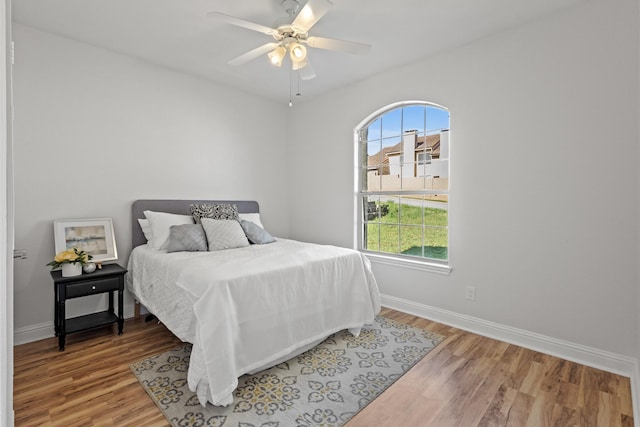 bedroom featuring a ceiling fan, baseboards, and light wood-style floors
