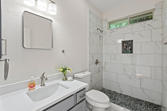 bathroom featuring vanity, toilet, and tiled shower
