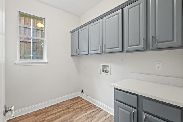 clothes washing area with hookup for a washing machine, cabinet space, hookup for a gas dryer, baseboards, and light wood-type flooring