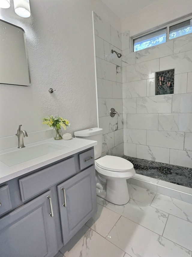 bathroom featuring vanity, toilet, and tiled shower