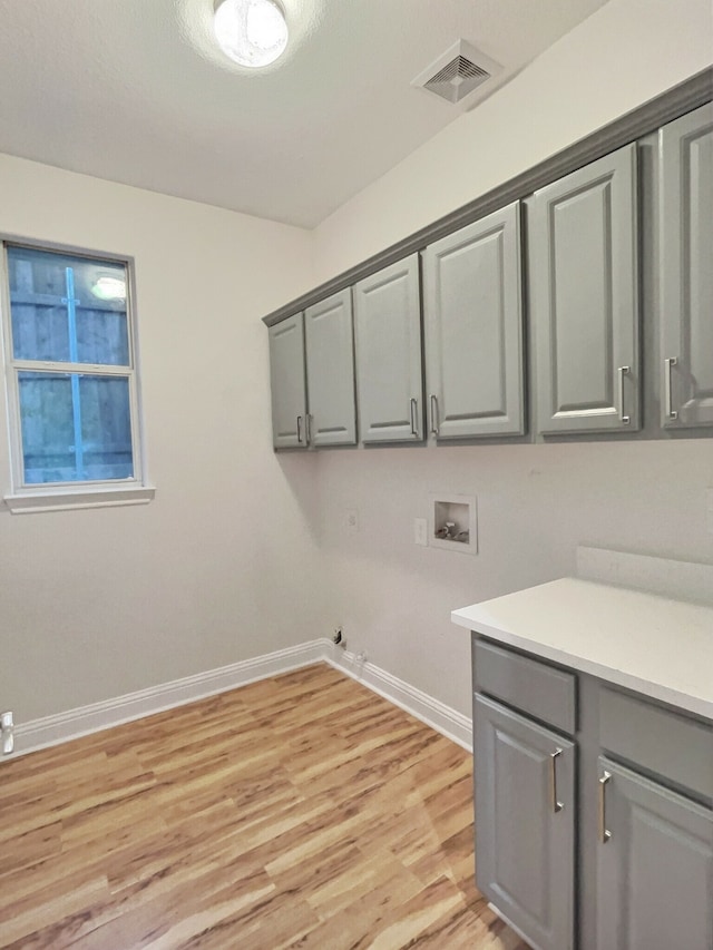 laundry area with gas dryer hookup, light hardwood / wood-style floors, cabinets, and hookup for a washing machine