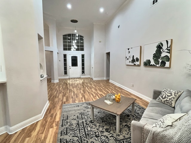 living room featuring a notable chandelier, wood-type flooring, and a high ceiling