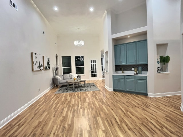 living room featuring light hardwood / wood-style flooring, a high ceiling, and a notable chandelier