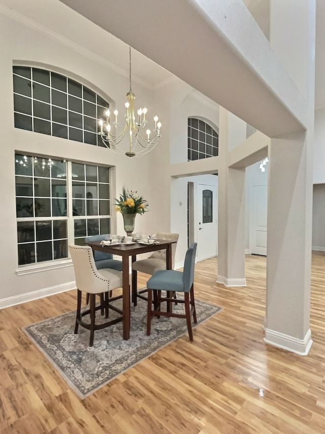 dining area with a high ceiling, a notable chandelier, and hardwood / wood-style floors