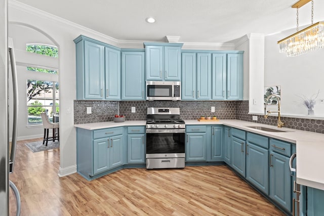 kitchen with a sink, stainless steel appliances, blue cabinetry, crown molding, and light countertops