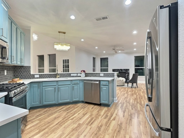 kitchen featuring decorative backsplash, stainless steel appliances, decorative light fixtures, light hardwood / wood-style flooring, and lofted ceiling