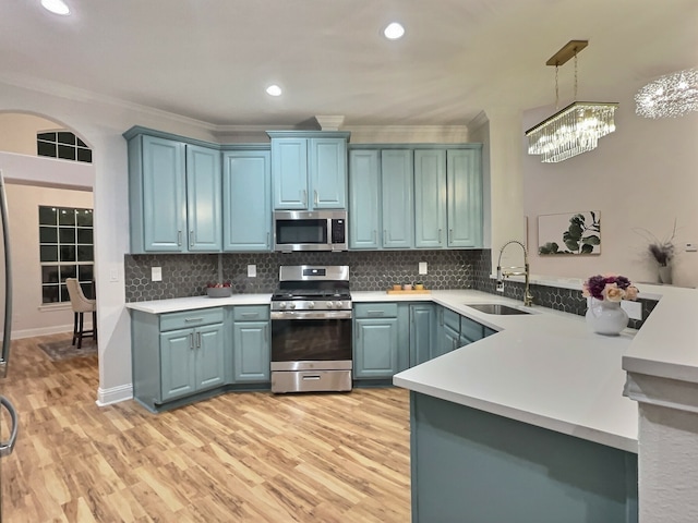 kitchen featuring sink, hanging light fixtures, kitchen peninsula, stainless steel appliances, and a chandelier