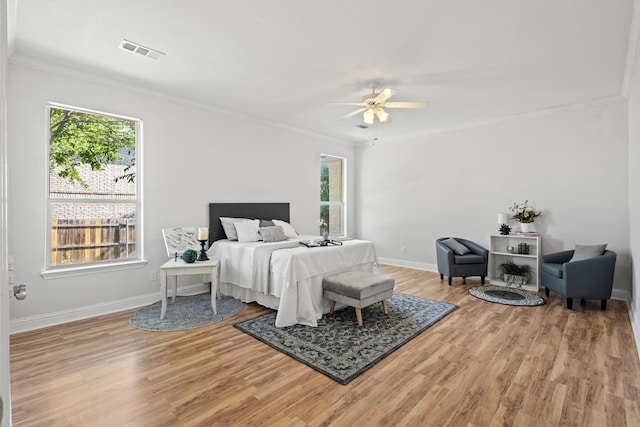 bedroom featuring crown molding, visible vents, ceiling fan, baseboards, and wood finished floors