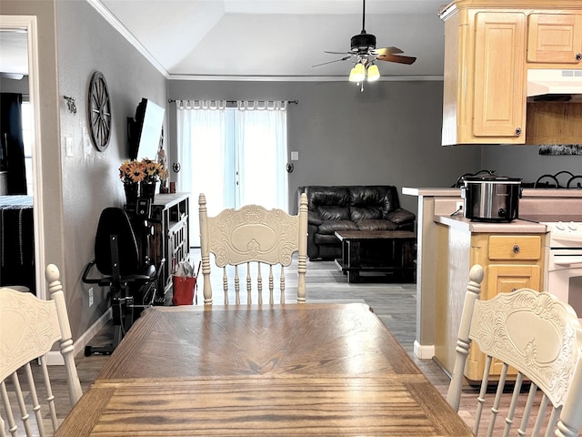 dining space with ceiling fan, light hardwood / wood-style floors, ornamental molding, and vaulted ceiling