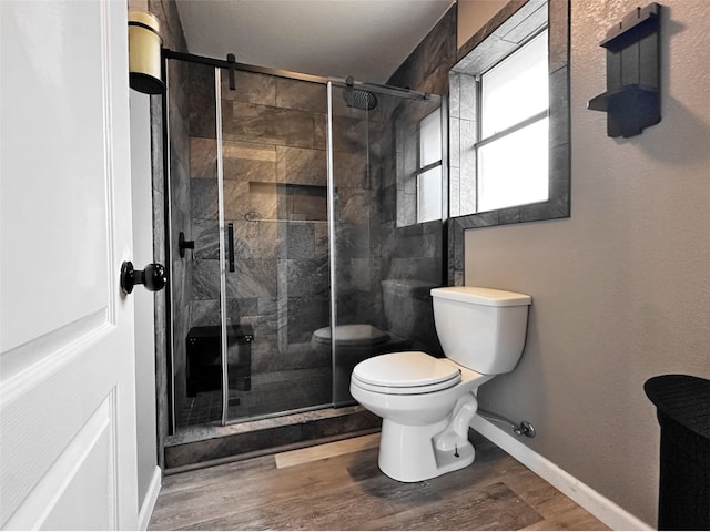 bathroom with hardwood / wood-style flooring, toilet, and a shower with shower door