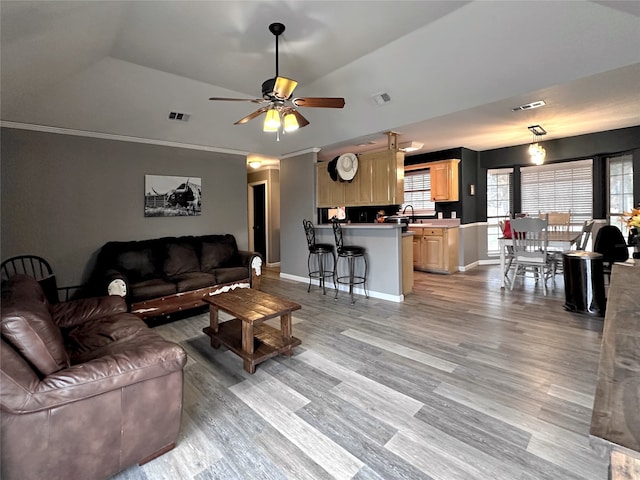 living room featuring lofted ceiling, light hardwood / wood-style flooring, ceiling fan, and ornamental molding