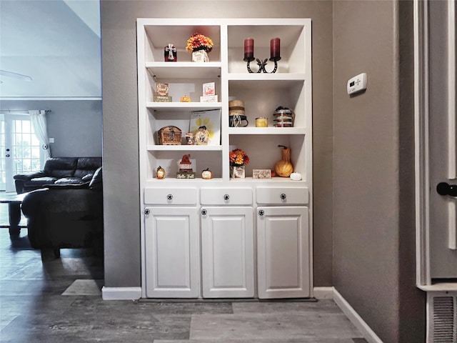 interior space with white cabinets, dark hardwood / wood-style floors, built in features, and ceiling fan