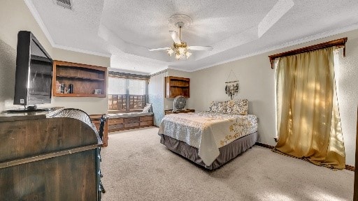 carpeted bedroom featuring a tray ceiling, ceiling fan, and crown molding