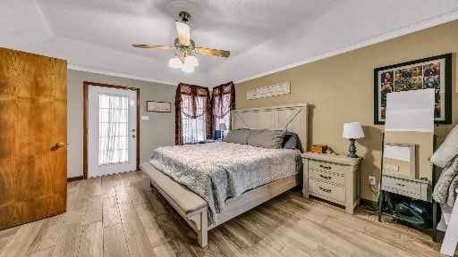 bedroom with a raised ceiling, ceiling fan, light wood-type flooring, a textured ceiling, and ornamental molding