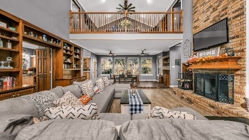 living room with a fireplace, a towering ceiling, hardwood / wood-style flooring, and ceiling fan