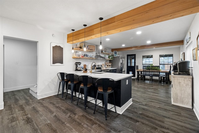 kitchen featuring dark hardwood / wood-style flooring, kitchen peninsula, pendant lighting, a kitchen bar, and appliances with stainless steel finishes