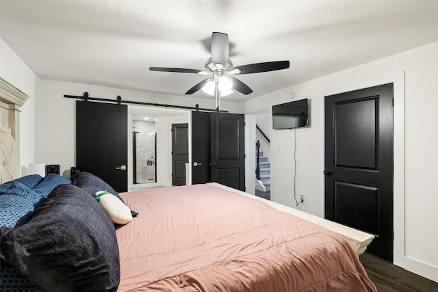 bedroom featuring a barn door, ceiling fan, and dark wood-type flooring