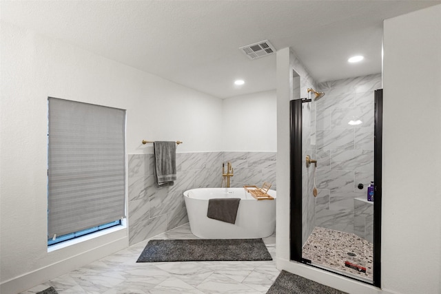 bathroom with shower with separate bathtub and tile walls