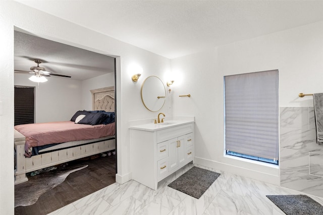 bathroom with ceiling fan, vanity, and a textured ceiling