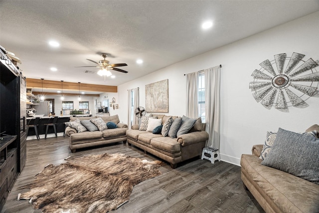 living room with a textured ceiling, dark hardwood / wood-style flooring, and ceiling fan