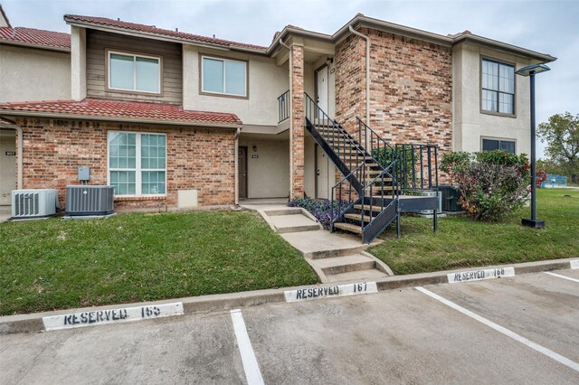 view of property featuring central air condition unit and a front yard