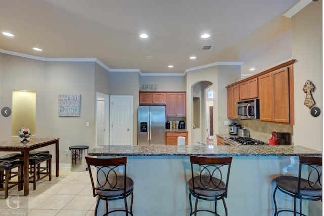 kitchen with kitchen peninsula, a kitchen breakfast bar, backsplash, and stainless steel appliances