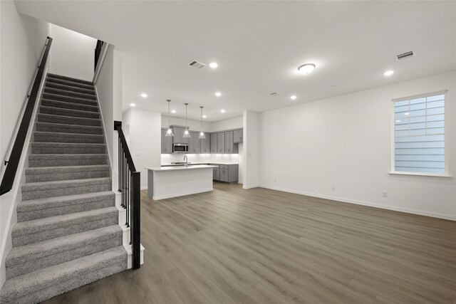 unfurnished living room featuring sink and dark wood-type flooring