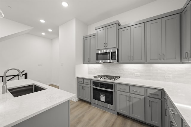 kitchen featuring gray cabinetry, sink, stainless steel appliances, and light hardwood / wood-style flooring