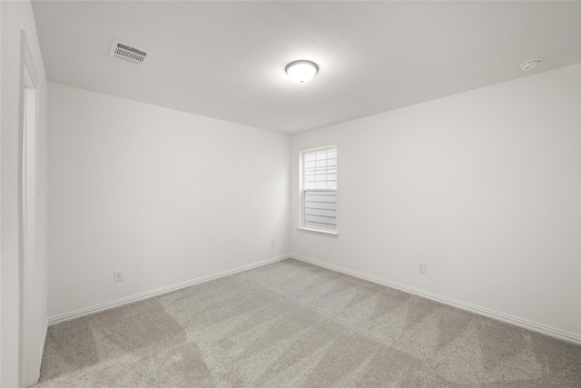 empty room featuring a textured ceiling and light colored carpet