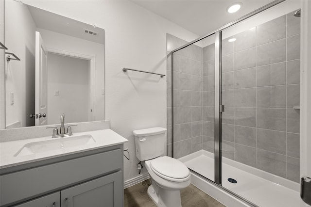 bathroom with a shower with door, vanity, hardwood / wood-style floors, and toilet