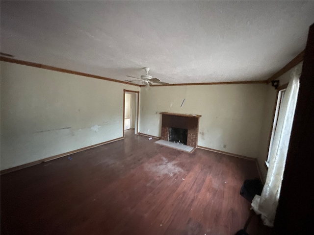 unfurnished living room with ceiling fan, dark wood-type flooring, crown molding, a textured ceiling, and a fireplace