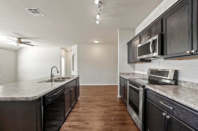 kitchen with stainless steel appliances, ceiling fan, dark wood-type flooring, sink, and an island with sink