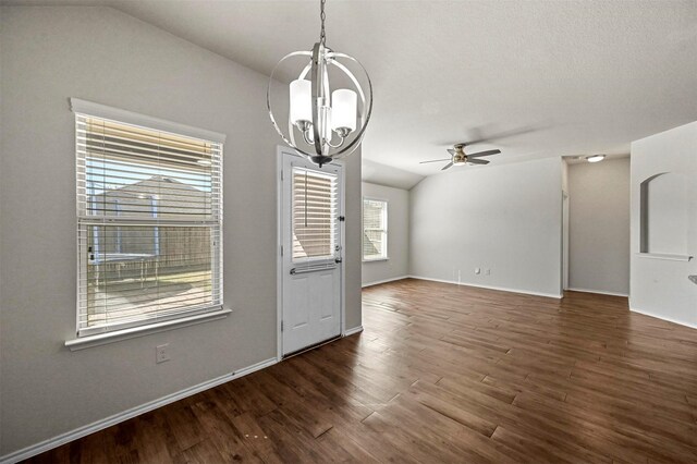 interior space with ceiling fan with notable chandelier, vaulted ceiling, and dark wood-type flooring