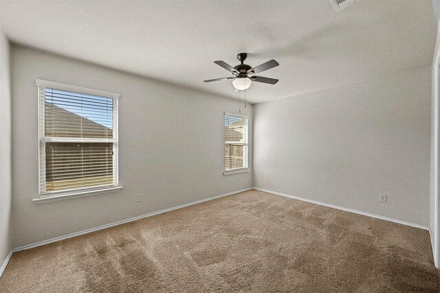 carpeted empty room with ceiling fan and a wealth of natural light