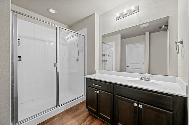 bathroom featuring hardwood / wood-style flooring, vanity, a shower with door, and a textured ceiling