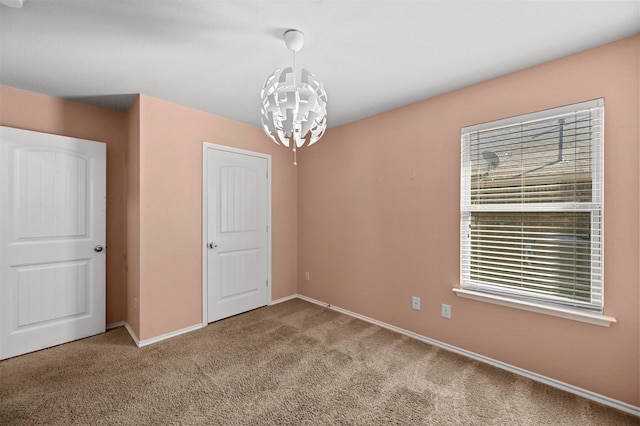 carpeted spare room with a notable chandelier