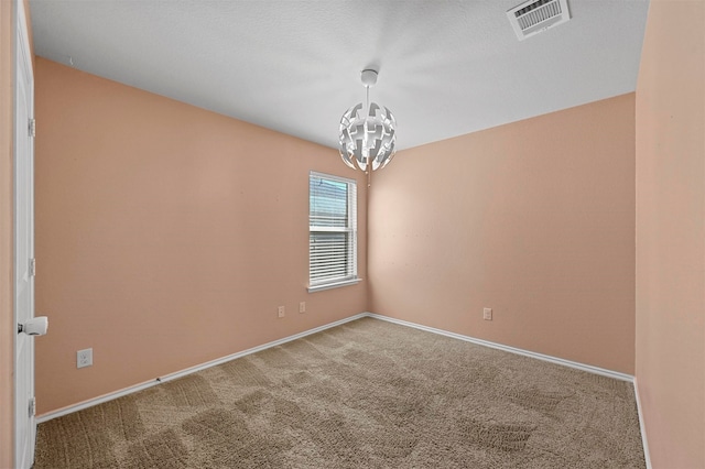 unfurnished room featuring carpet flooring, a notable chandelier, and a textured ceiling